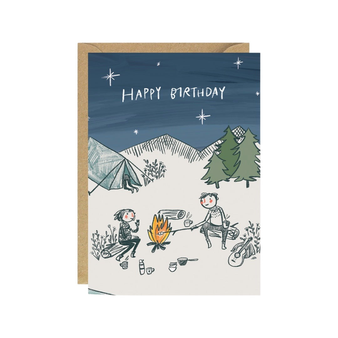 Birthday card featuring an illustration of a couple out camping in the woods sitting around a campfire.