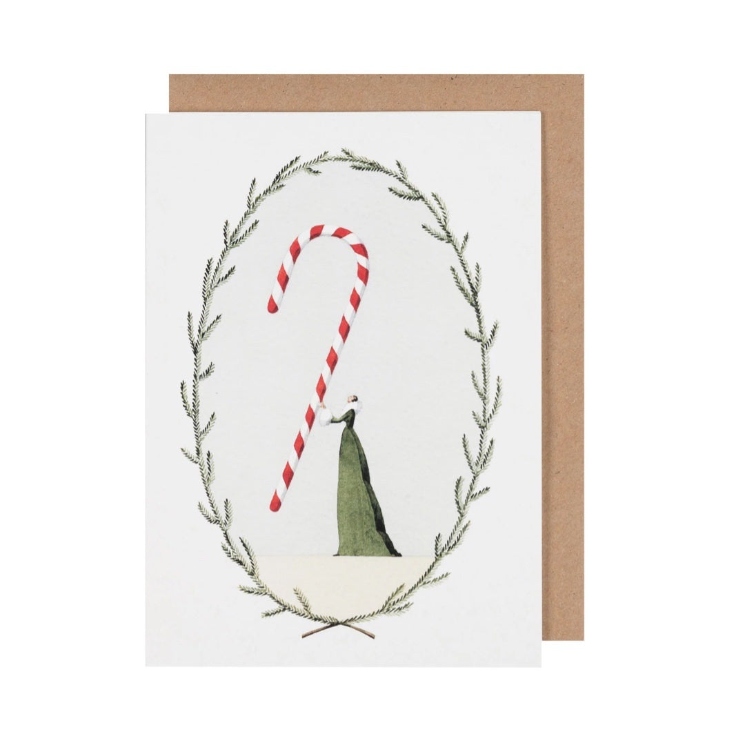 Christmas card featuring a lady in a beautiful green dress holding a giant red and white striped candy cane, framed by green foliage.