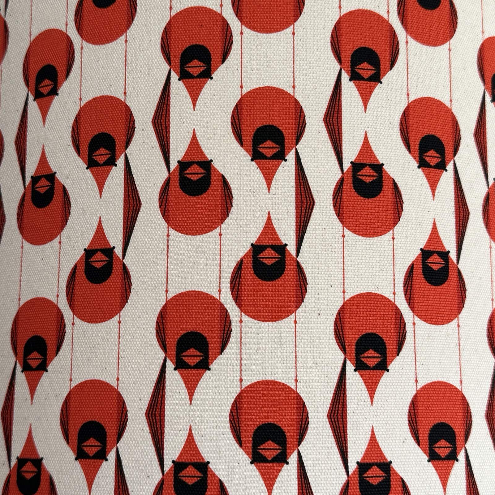 Pattern of red and black abstract shapes on a beige lampshade.