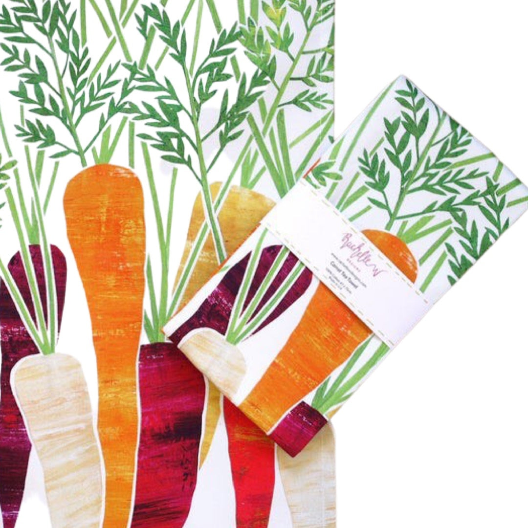 Folded carrot tea towel featuring purple, orange and cream carrots with green leaves on a white background.