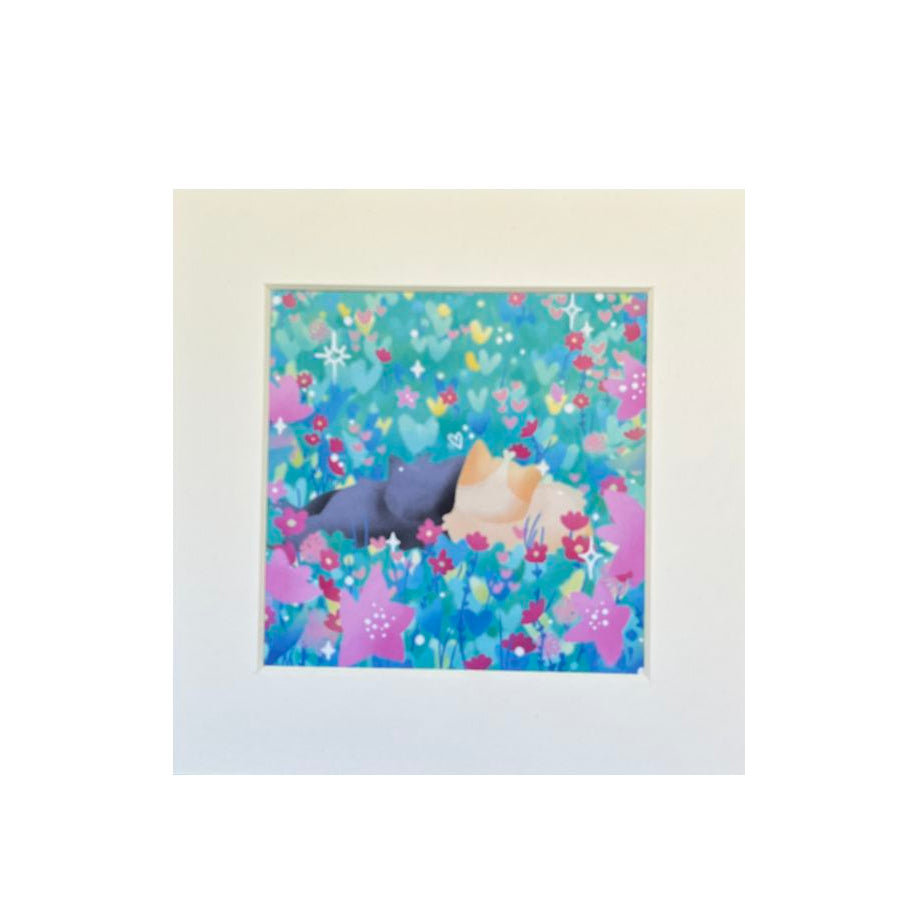 Illustrated print of a black cat and a ginger cat cuddling in a teal, pink, blue, and yellow flower field of hearts.