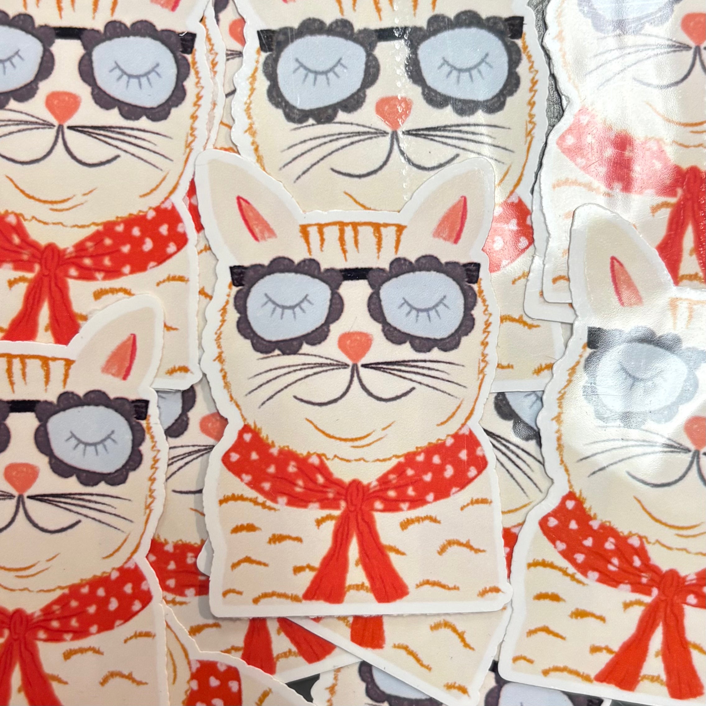 Stickers of cats with sunglasses and red bows on a patterned background.