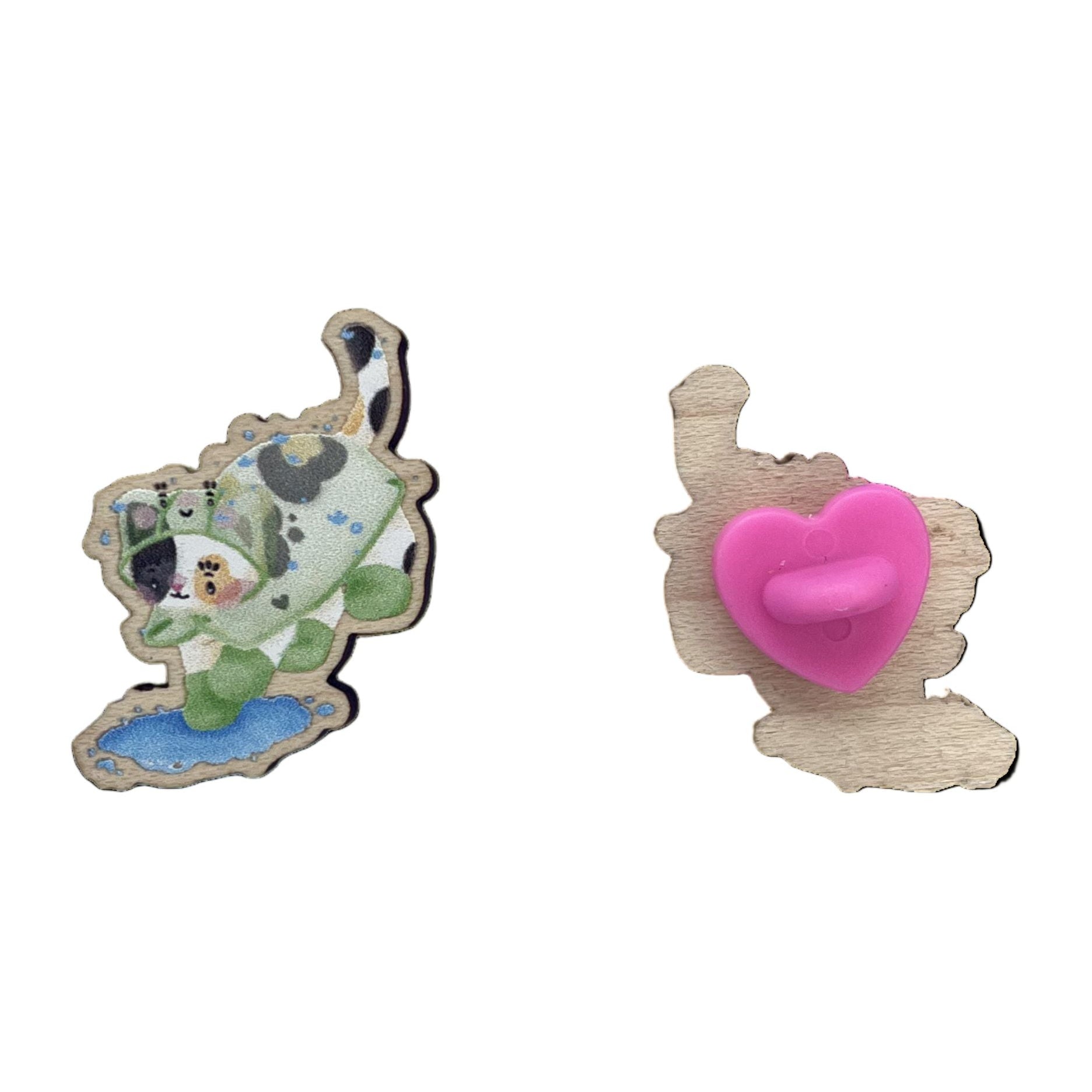 Front (left) and back (right) of a wooden pin badge of a calico cat wearing a frog raincoat and green rainboots, jumping into a puddle. 