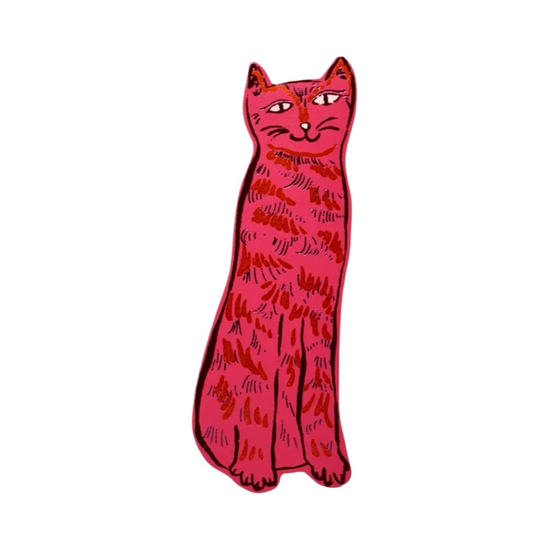 A cat-shaped leather bookmark in pink with black facial details and silver and red fur.