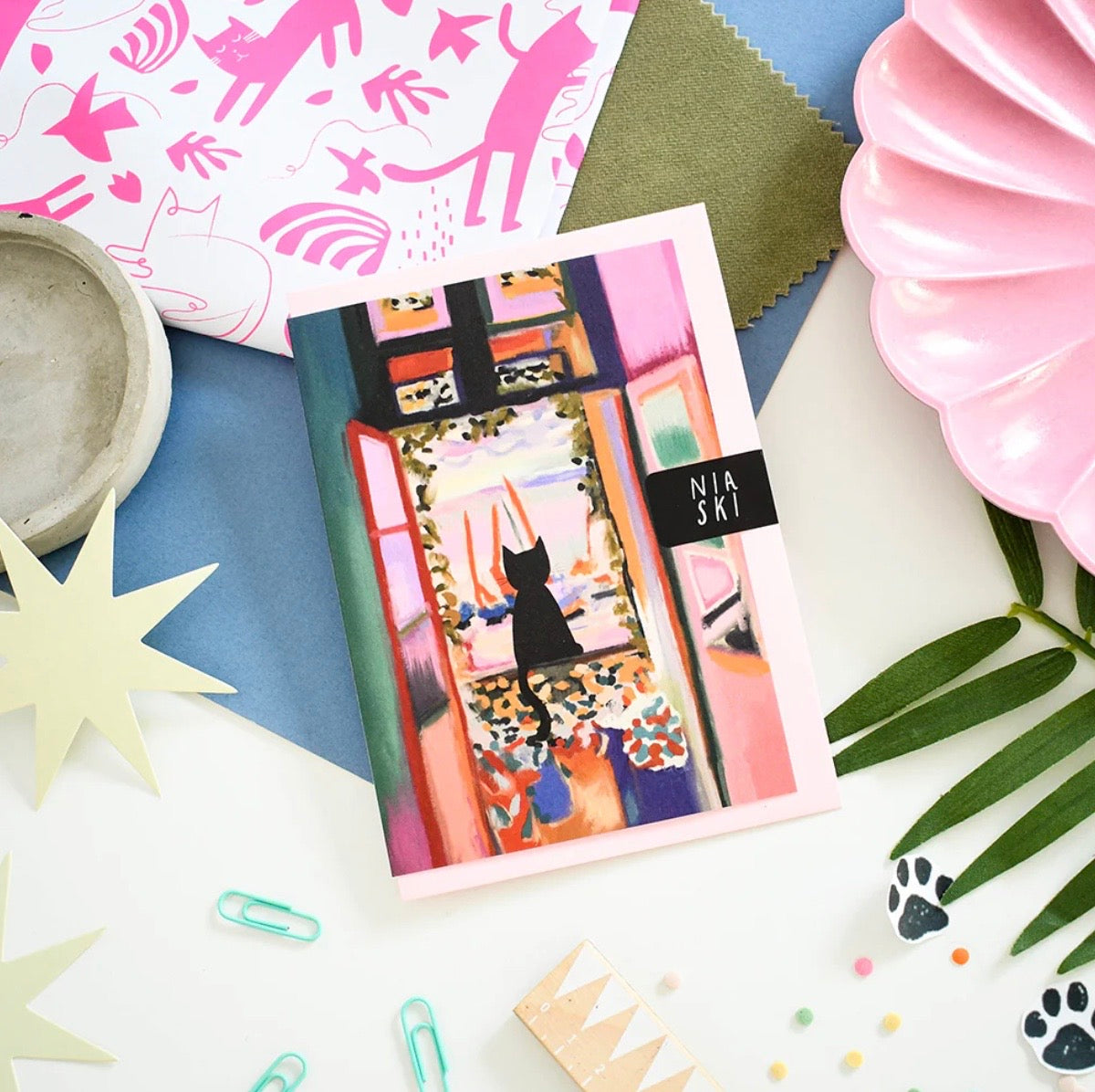 Pack of stationery items with a cat design on a colourful background.