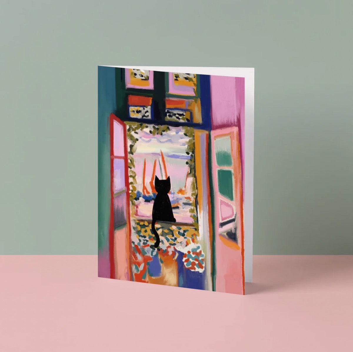 Greeting card with a colourful abstract design featuring a cat, on a pink surface with a grey background.