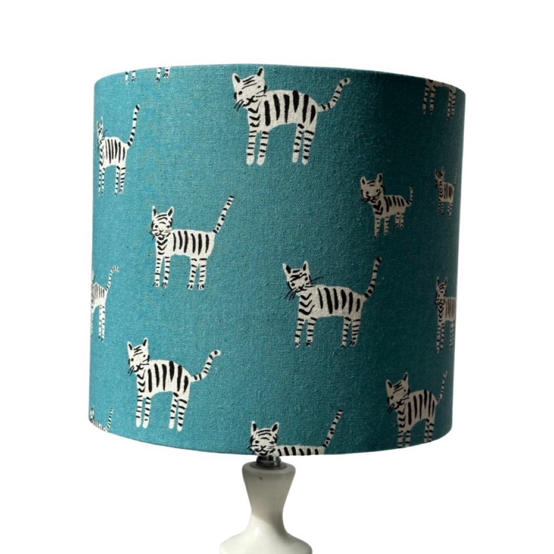 Drum lampshade in blue with hand drawn black and white cats on a white lamp base.