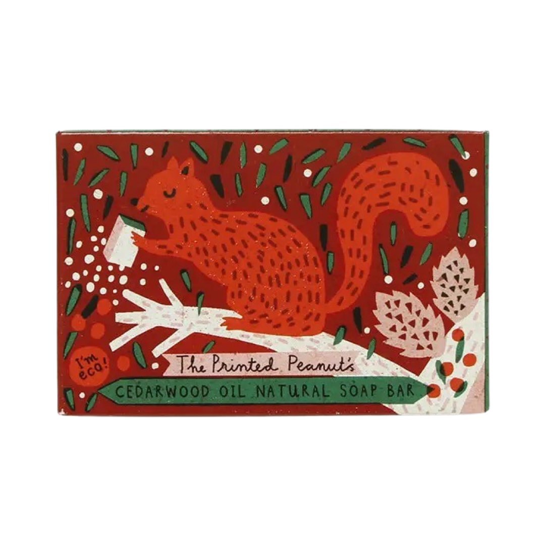 A red and green box of 'The Printed Peanut's Cedarwood Oil Natural Soap Bar' with an illustration of a peanut, pinecone, and leaves.