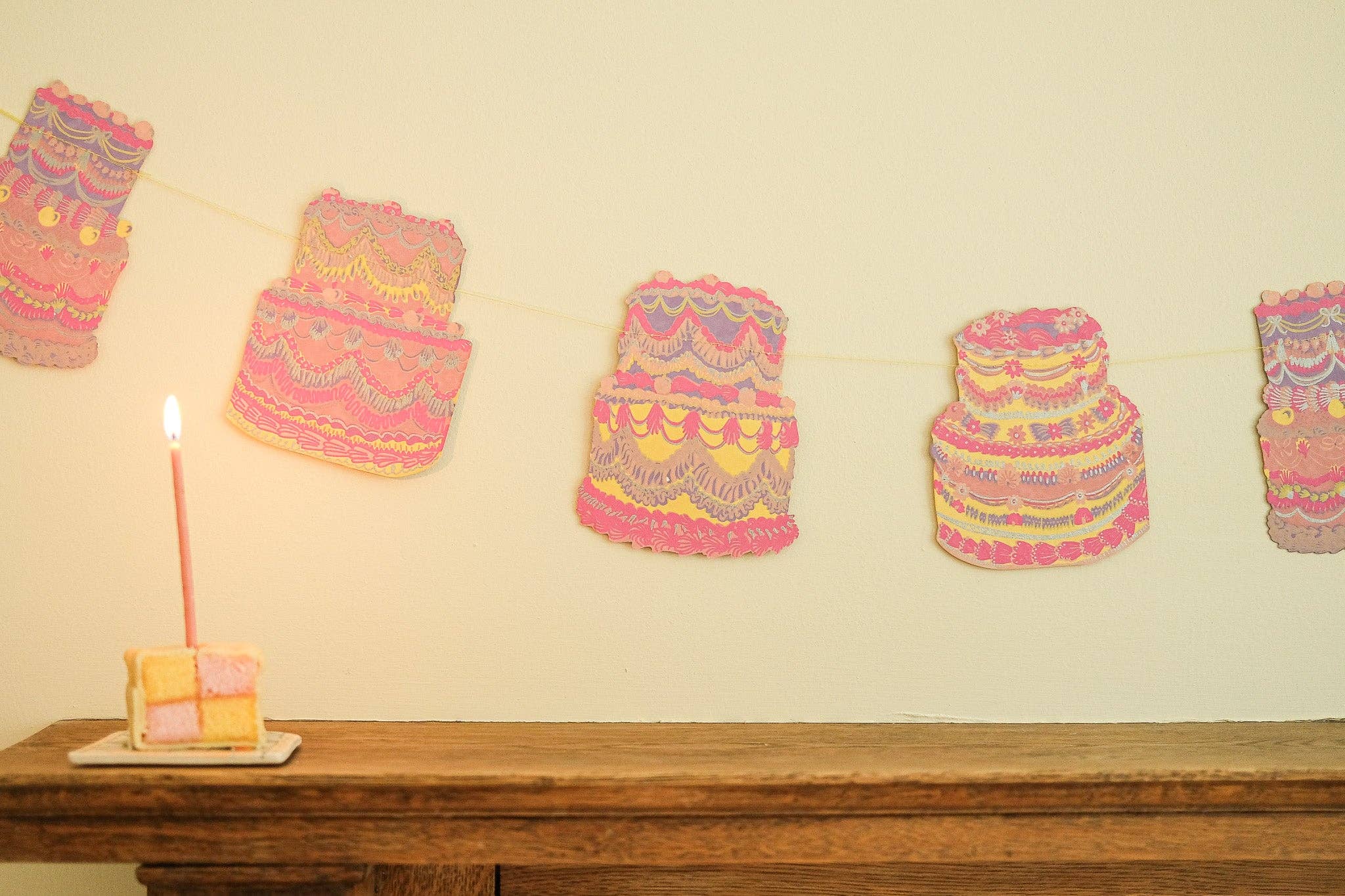 Decorative pink and yellow hats on a wooden surface with a candle.