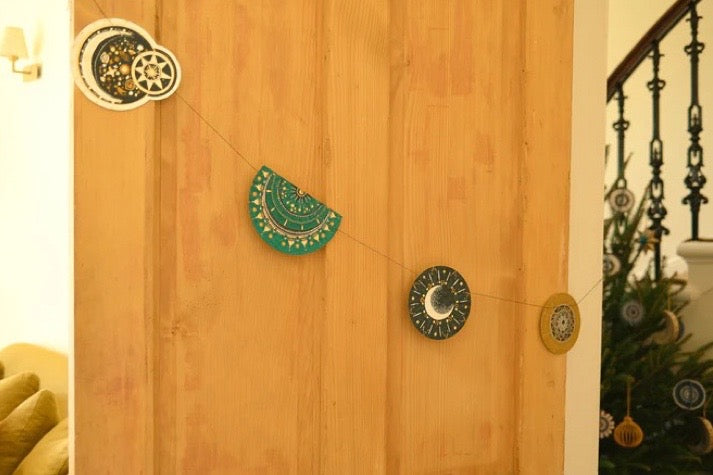 Decorative wall hangings on a wooden door with a Christmas tree in the background.