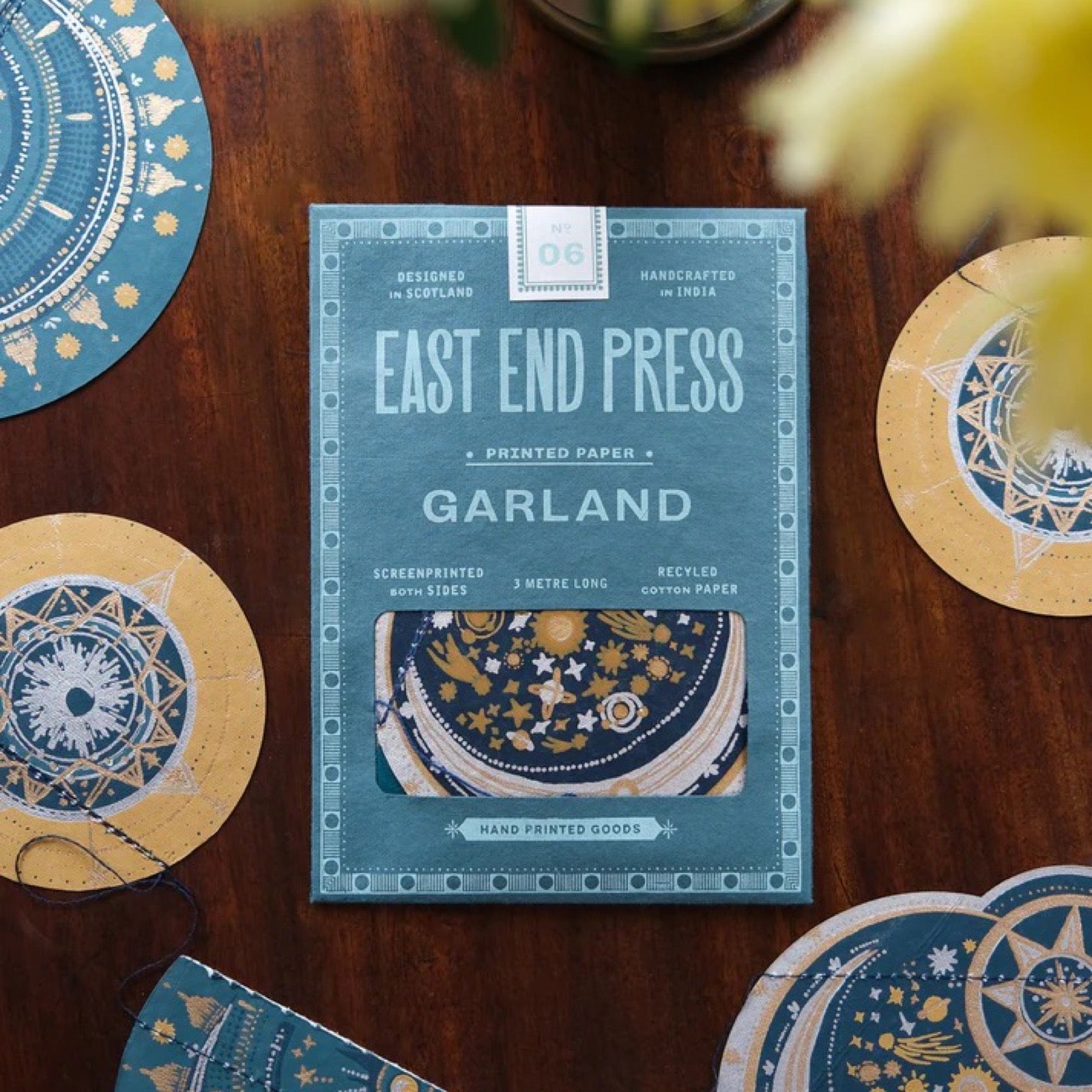 Packaging of East End Press Garland paper on a wooden surface with decorative papers around.