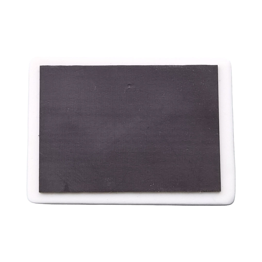 The back of a rectangular ceramic magnet with a magnetic strip. 