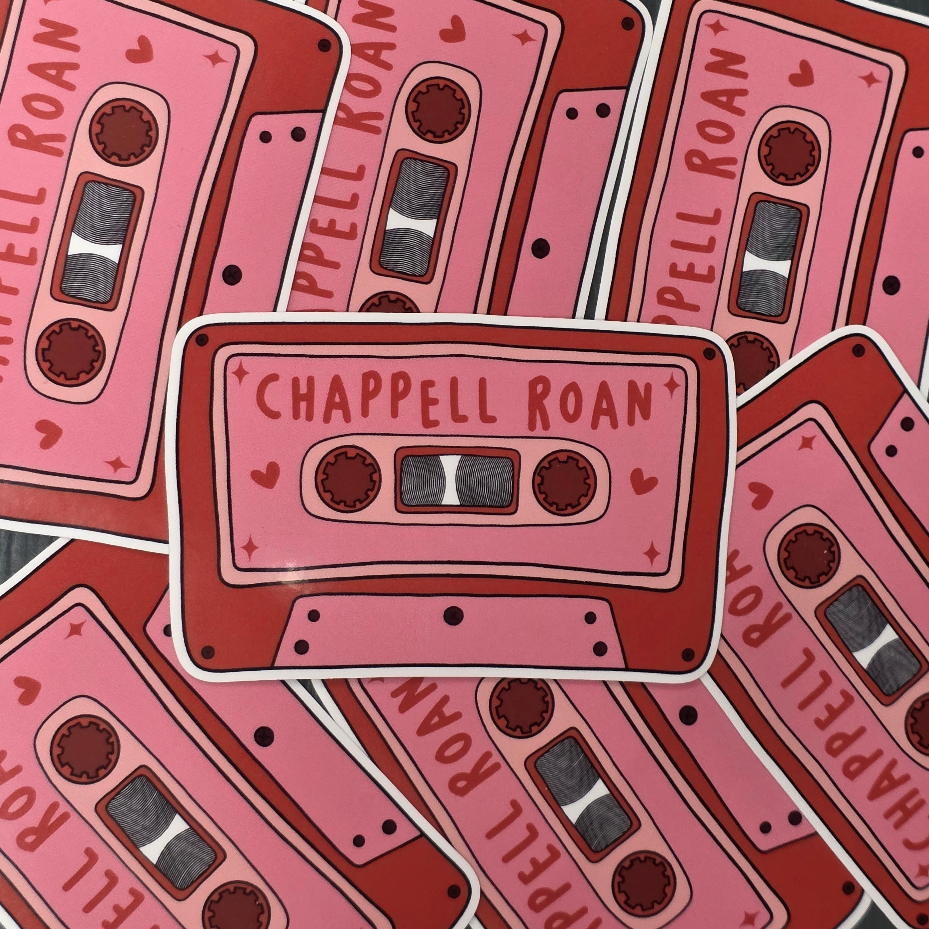 A rectangular-shaped sticker featuring an illustration of a retro cassette tape in pink and red with the title 'Chappell Roan', decorated with red love hearts.