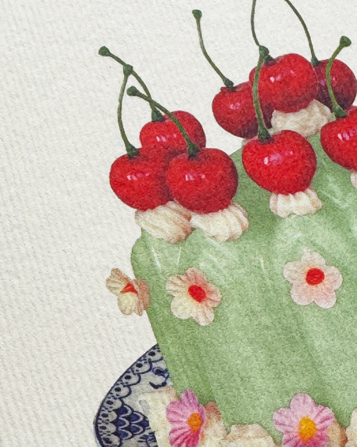 Close-up of a green cake with red cherries and floral decorations on a white background.