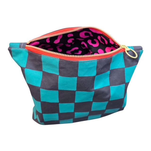 A screen-printed checked cosmetic bag in turquoise and grey with a yellow zip open to show pink leopard print lining.