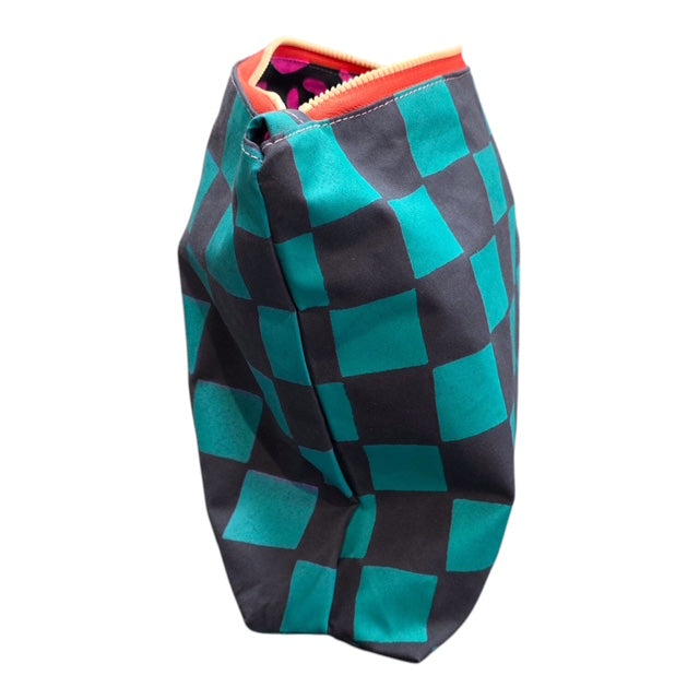 The end of a screen-printed checked cosmetic bag in turquoise and grey with a yellow zip open to show pink leopard print lining.