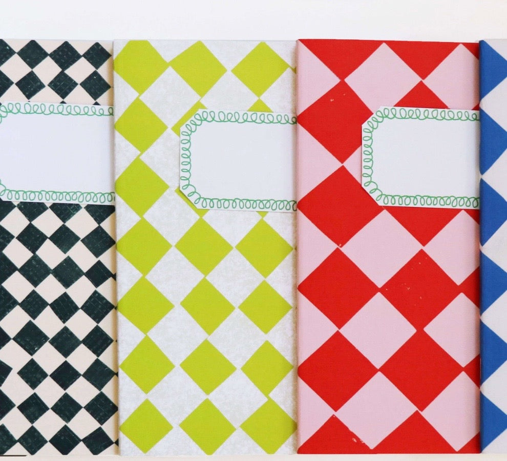 Four patterned paper notebooks with labels and decorative borders, shown in black-and-white, lime green-and-white, red-and-pink, and blue-and-white diamond checks.