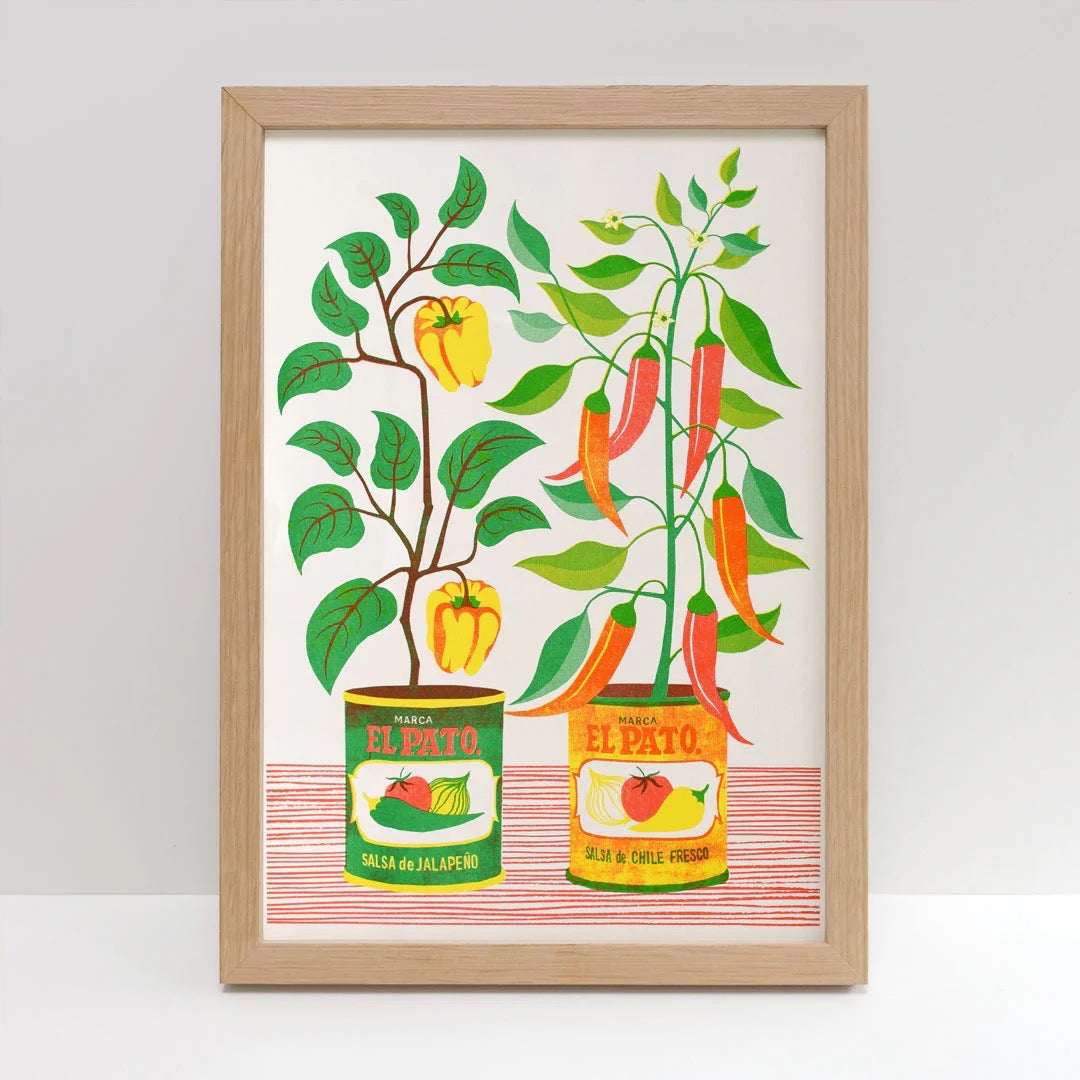 Framed artwork of peppers and El Pato cans on a white background.