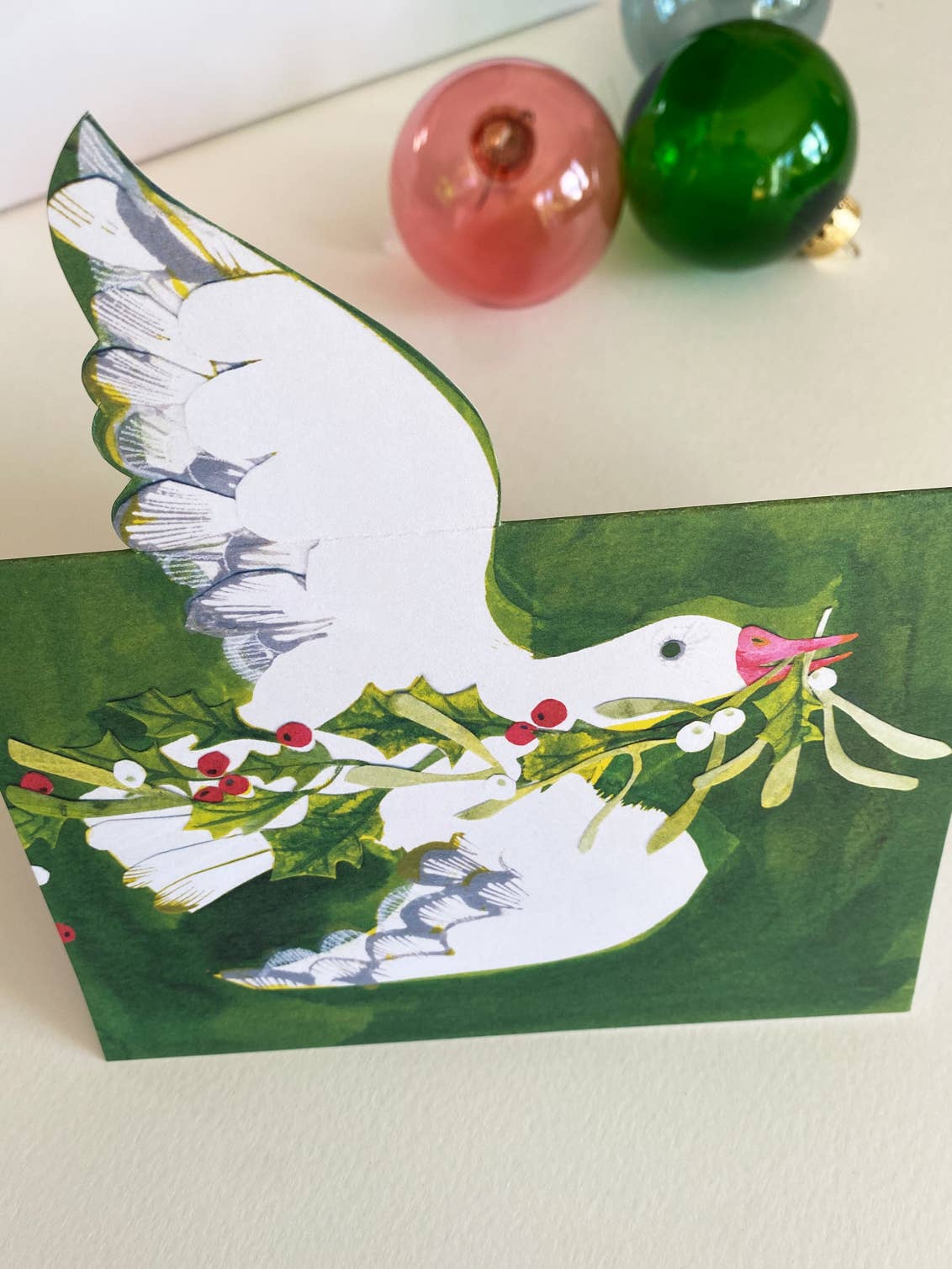 Card with a goose holding mistletoe on a green background.