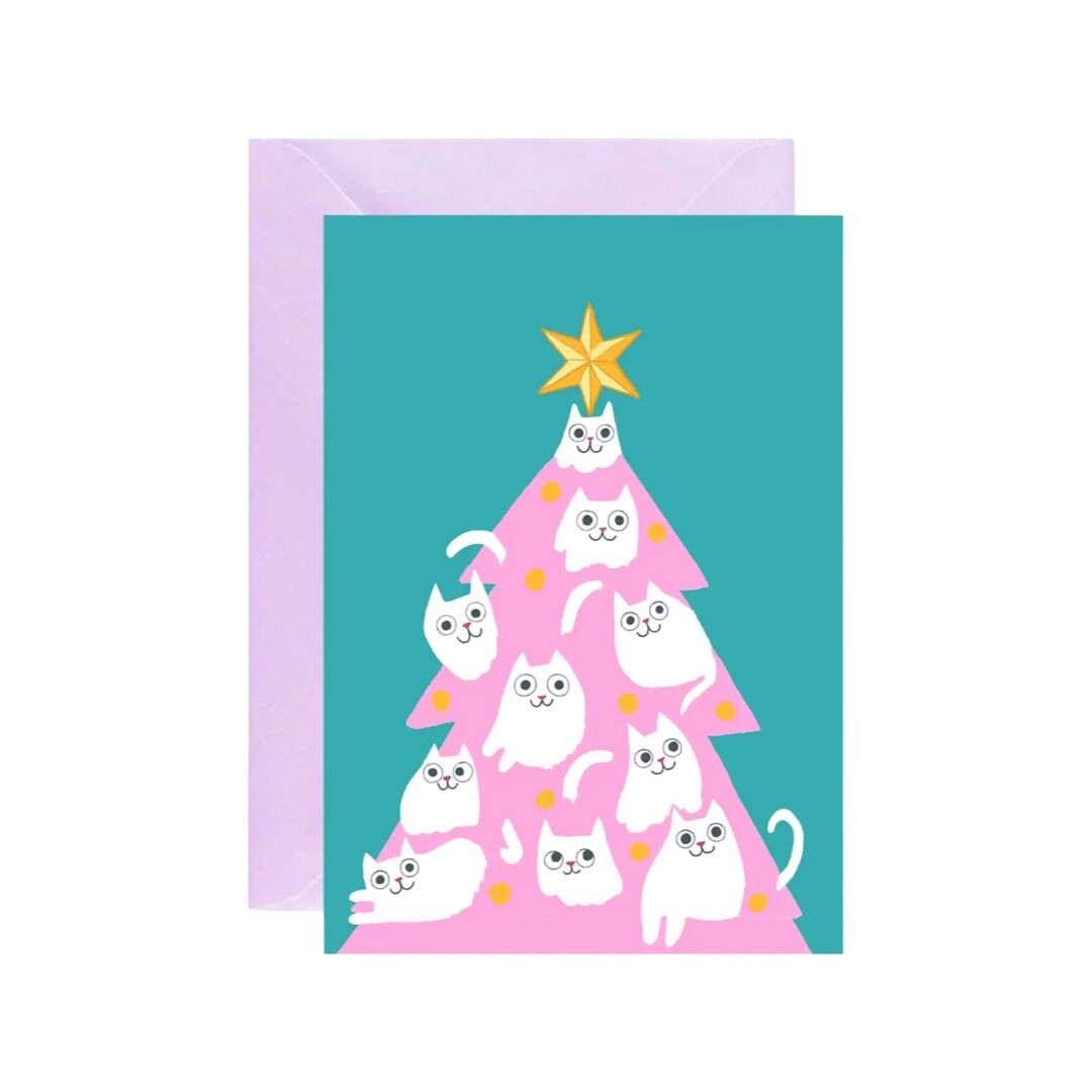 A greeting card with a pink Christmas tree and white kittens as baubles on a turquoise background, with a gold star at the top, and a lilac envelope.