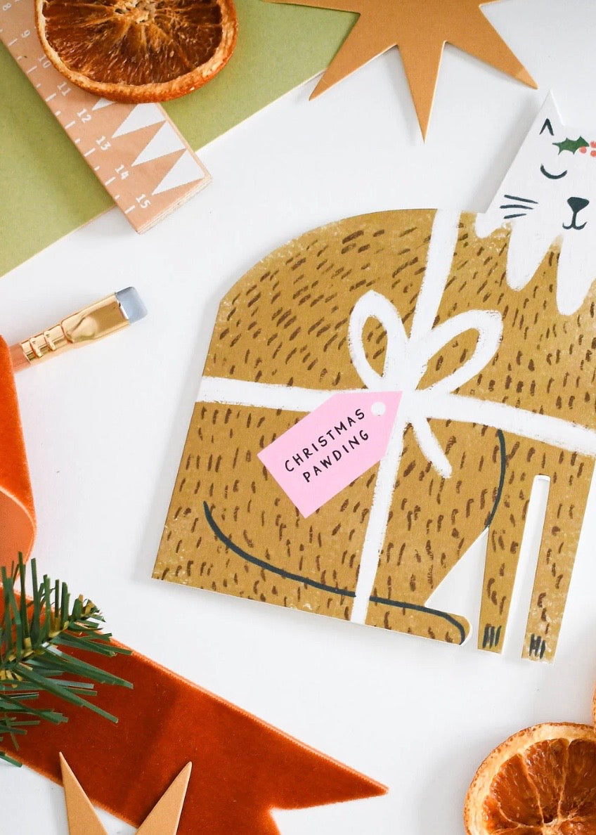 Decorative card with a cat design, Christmas pawding label, and festive elements on a white background.