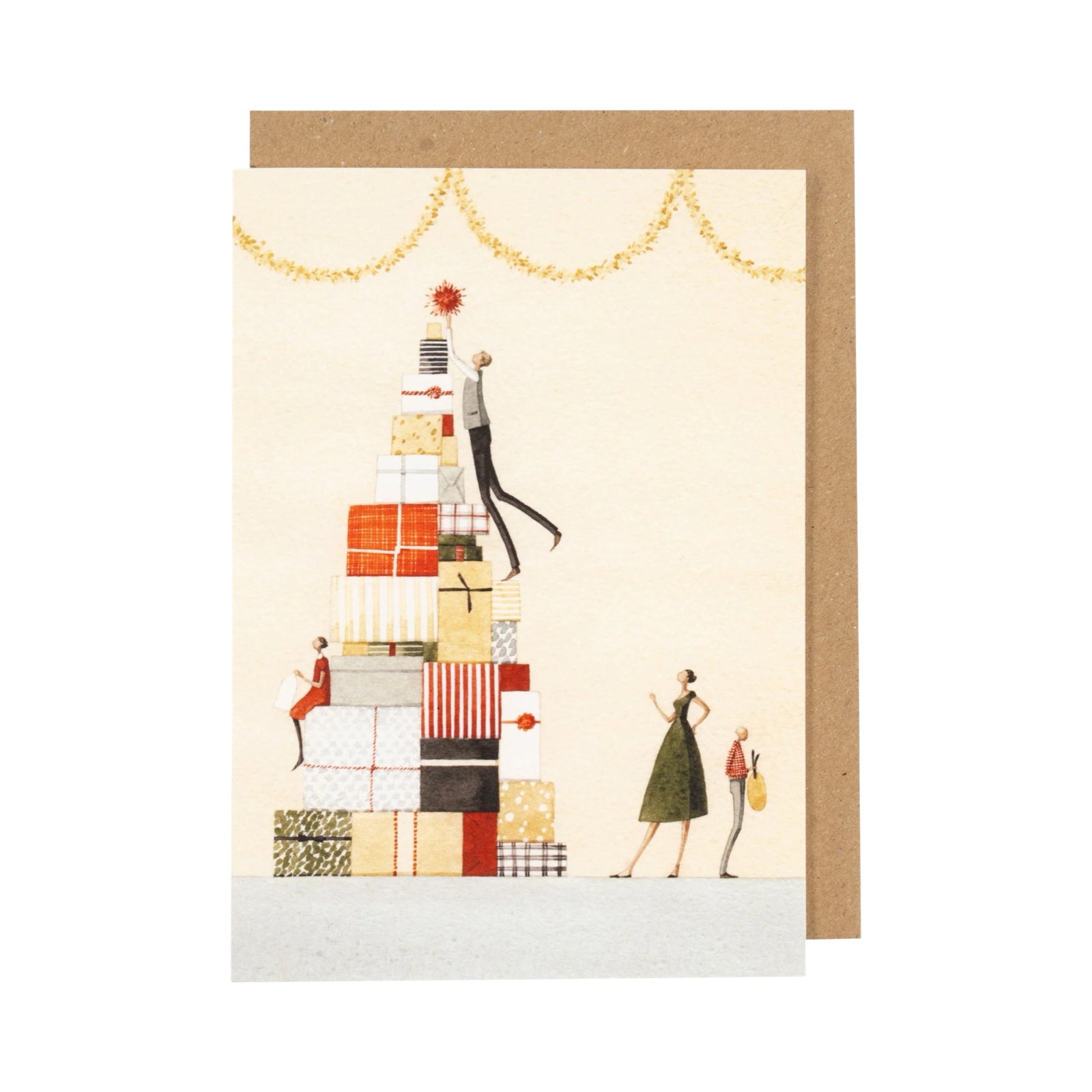  Christmas card featuring a family decorating a Christmas tree made out of Christmas presents. 