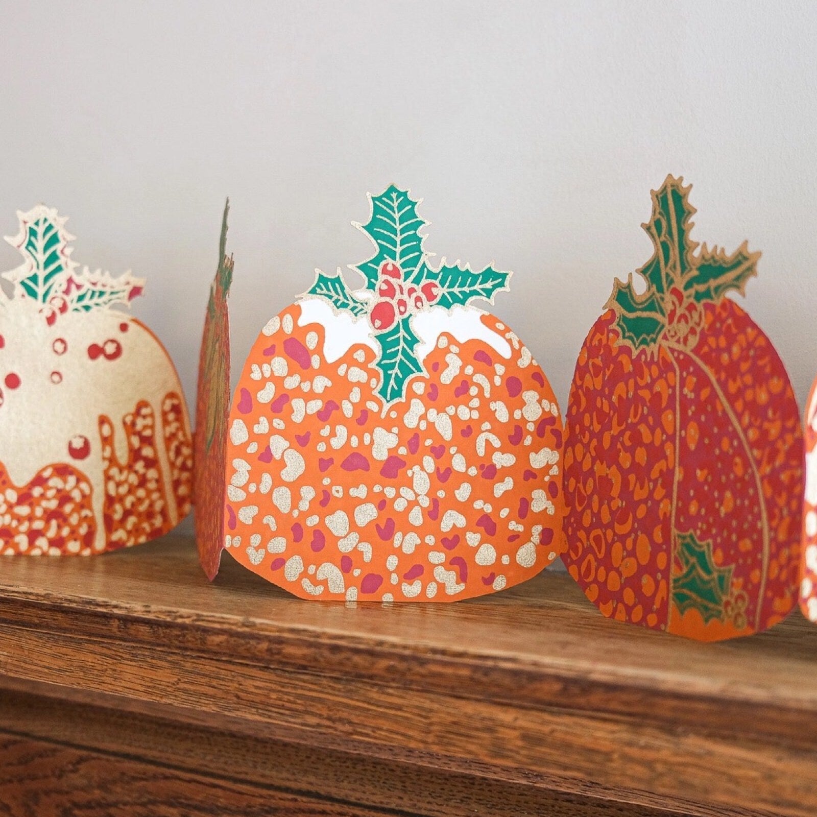 Christmas pudding paper concertina garland on a wooden shelf.