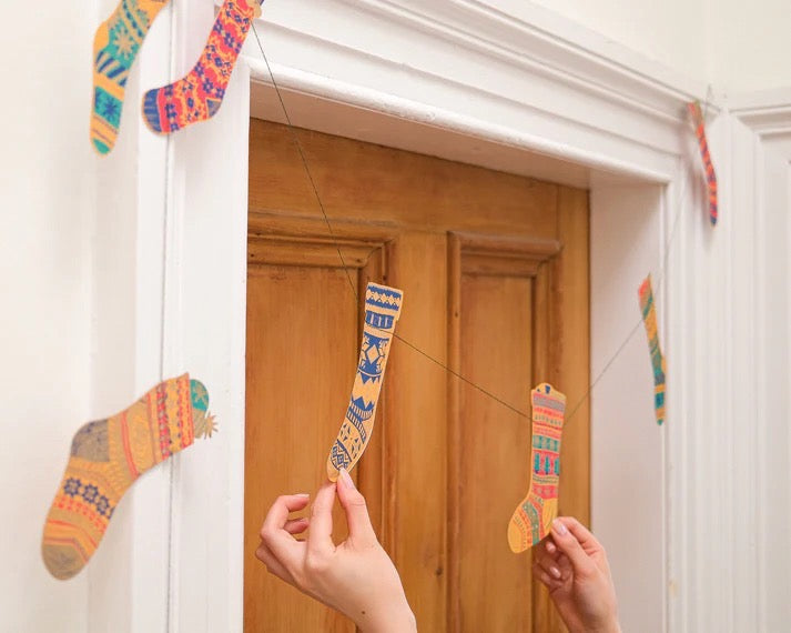 Colorful Christmas stockings hanging on a door with hands adjusting them.