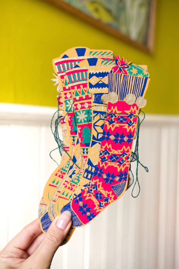 Colorful patterned stocking held by a hand against a yellow wall.