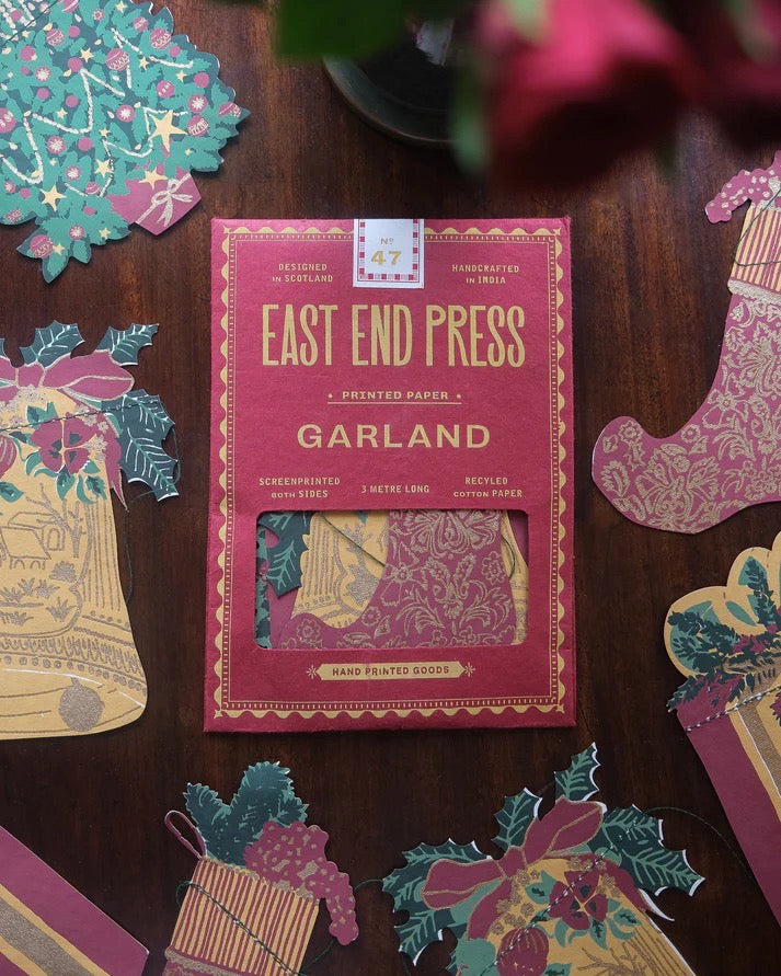 East End Press Garland packaging on a wooden surface with decorative paper pieces.