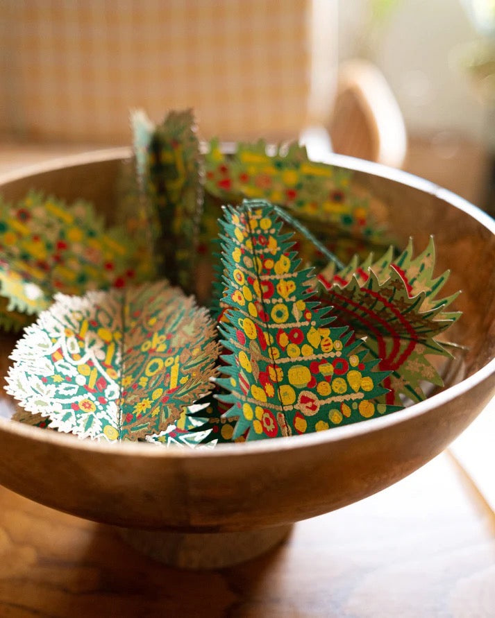 Colourful paper decorations in a wooden bowl on a wooden surface.