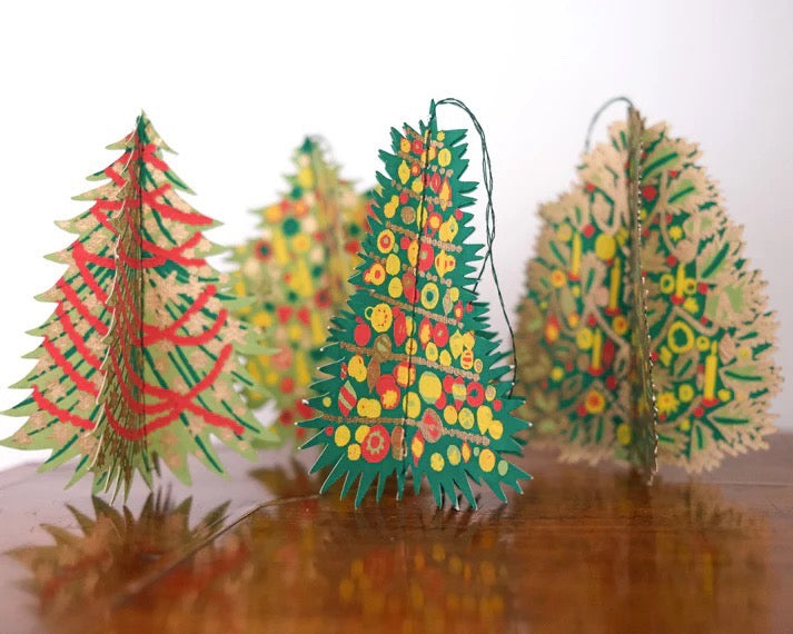 Colorful paper Christmas trees on a reflective surface with a white background.