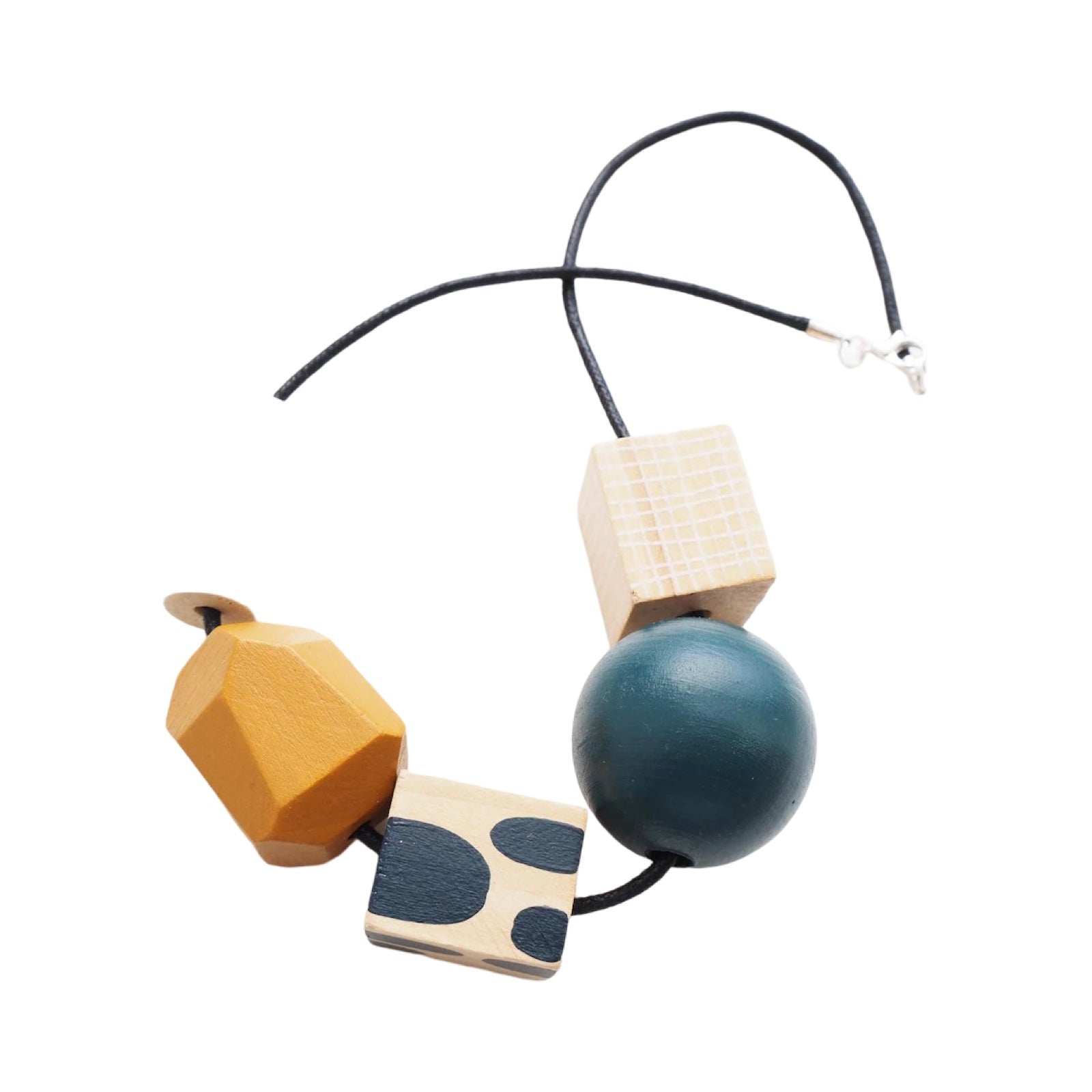 A chunky wooden necklace with 5 beads, 1 white cylindrical, 1 mustard, 1 blue polka dot cube, 1 blue sphere and 1 natural rectangle on a black cotton cord with a silver-plated fastening.