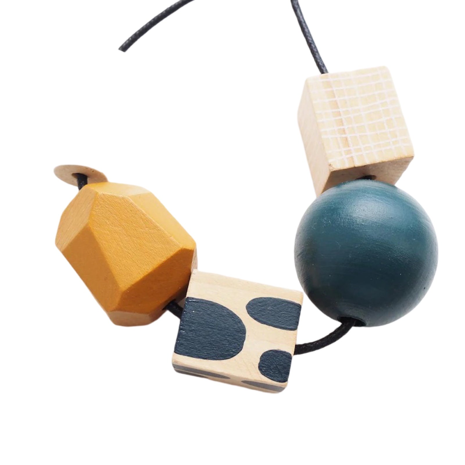 A chunky wooden necklace with 5 beads, 1 white cylindrical, 1 mustard, 1 blue polka dot cube, 1 blue sphere and 1 natural rectangle on a black cotton cord with a silver-plated fastening.