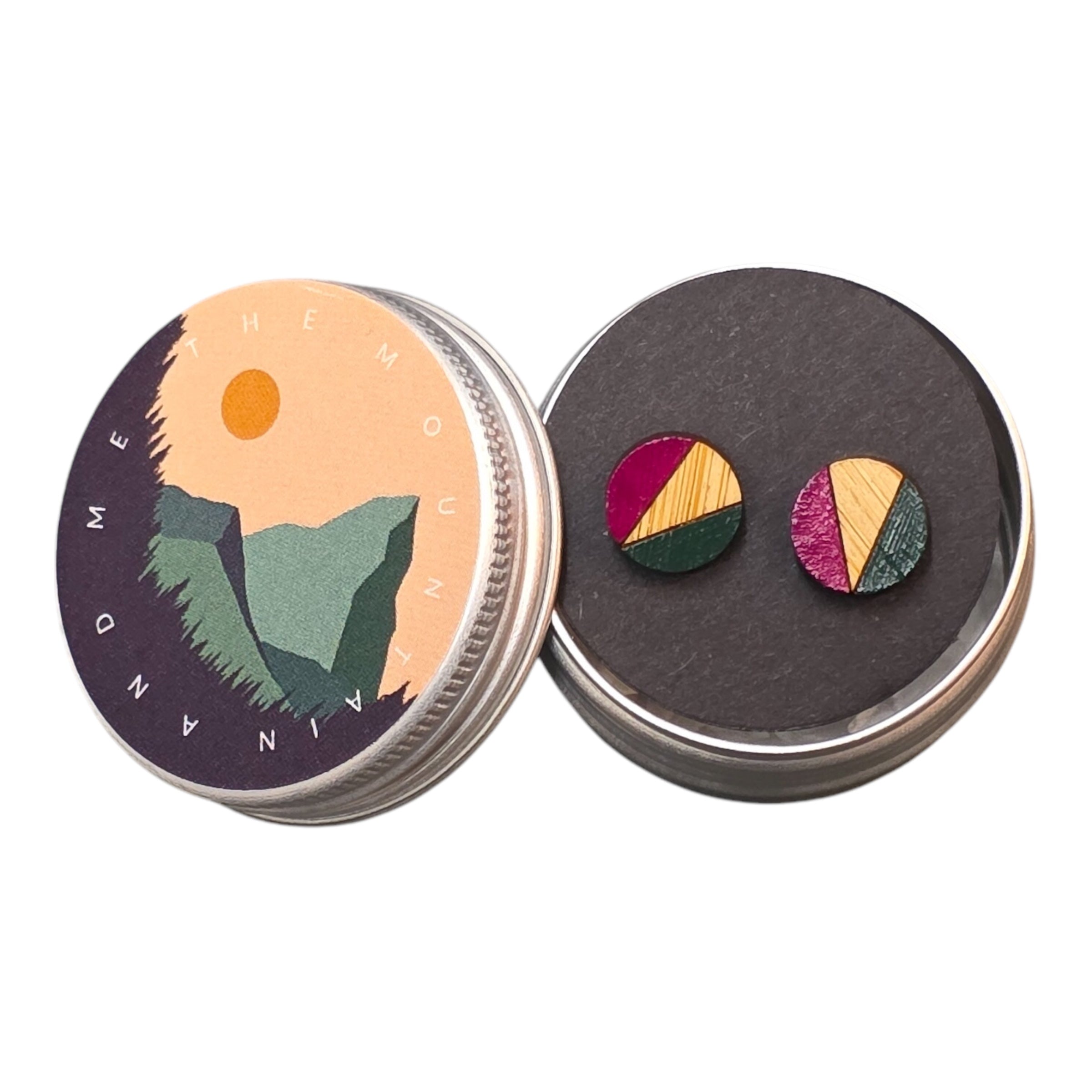 A pair of pink and navy painted circular wooden stud earrings in a small metal tin.