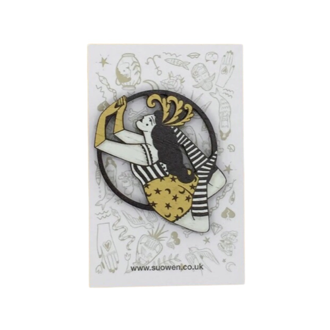 Circus aerialist wooden brooch featuring a female performer in a yellow and black costume with a feather headdress.