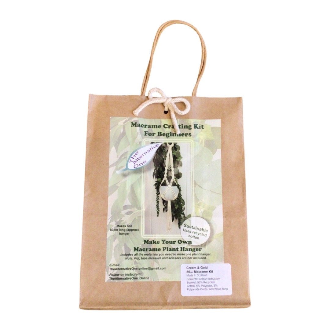 A Classic Macrame Plant Hanger Kit packaged in a brown paper bag displaying the contents, including pre-cut macrame cords and a wooden hanging ring.