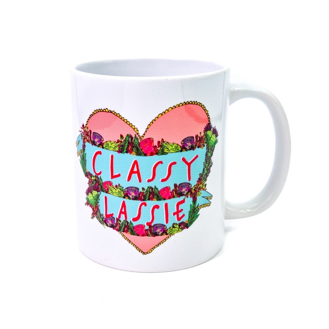 Mug featuring an illustration of a red love heart on a white background and the text 'Classy Lassie' written inside the heart in banners surrounded by flowers.