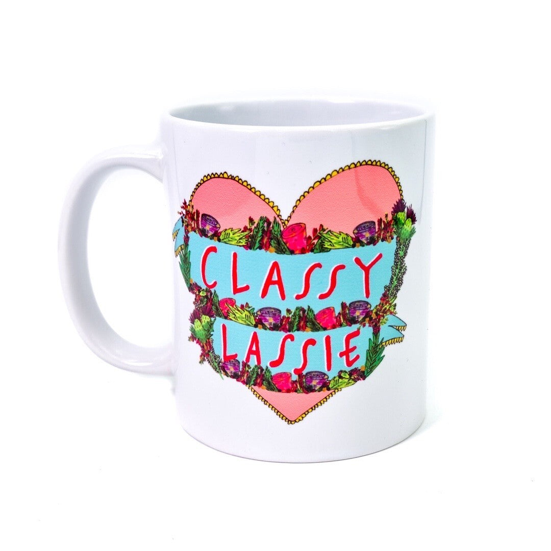 Mug featuring an illustration of a red love heart on a white background and the text 'Classy Lassie' written inside the heart in banners surrounded by flowers.