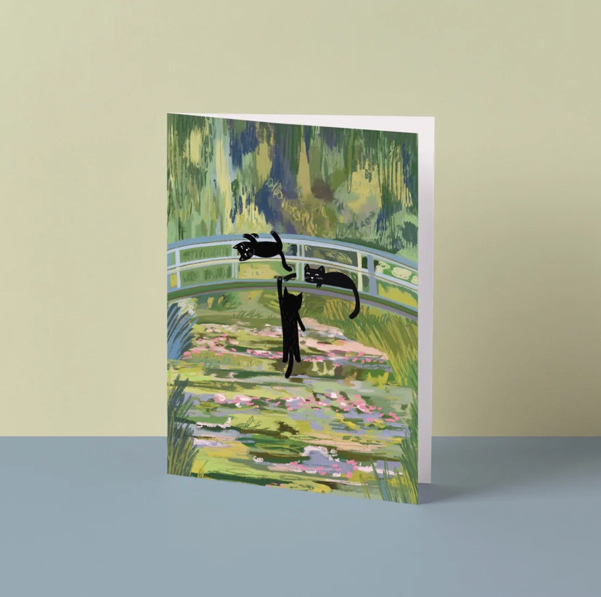 Greeting card with black cat design on a colourful landscape background.