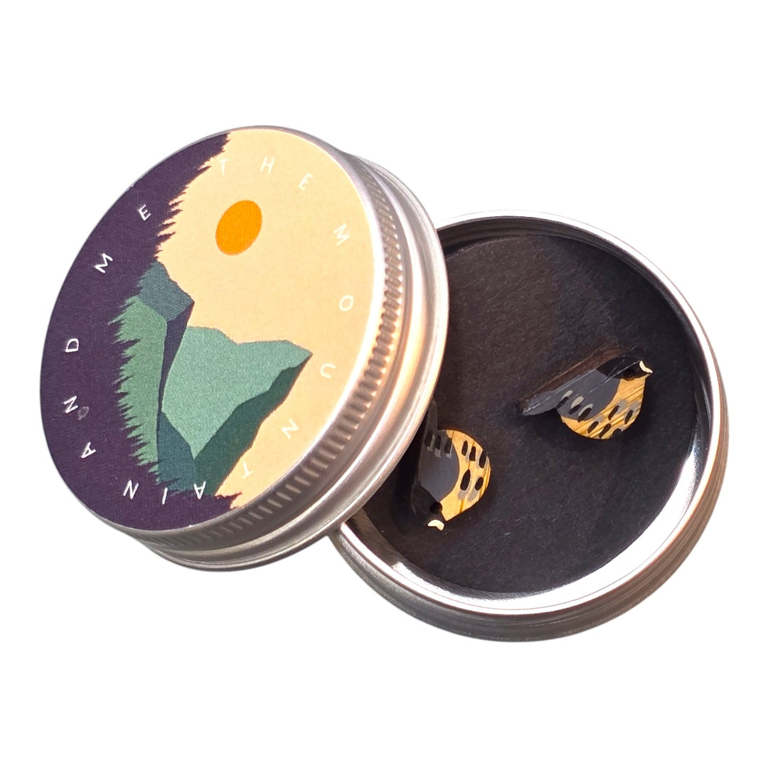 An image of small wooden earrings shaped like birds in a small tin. 