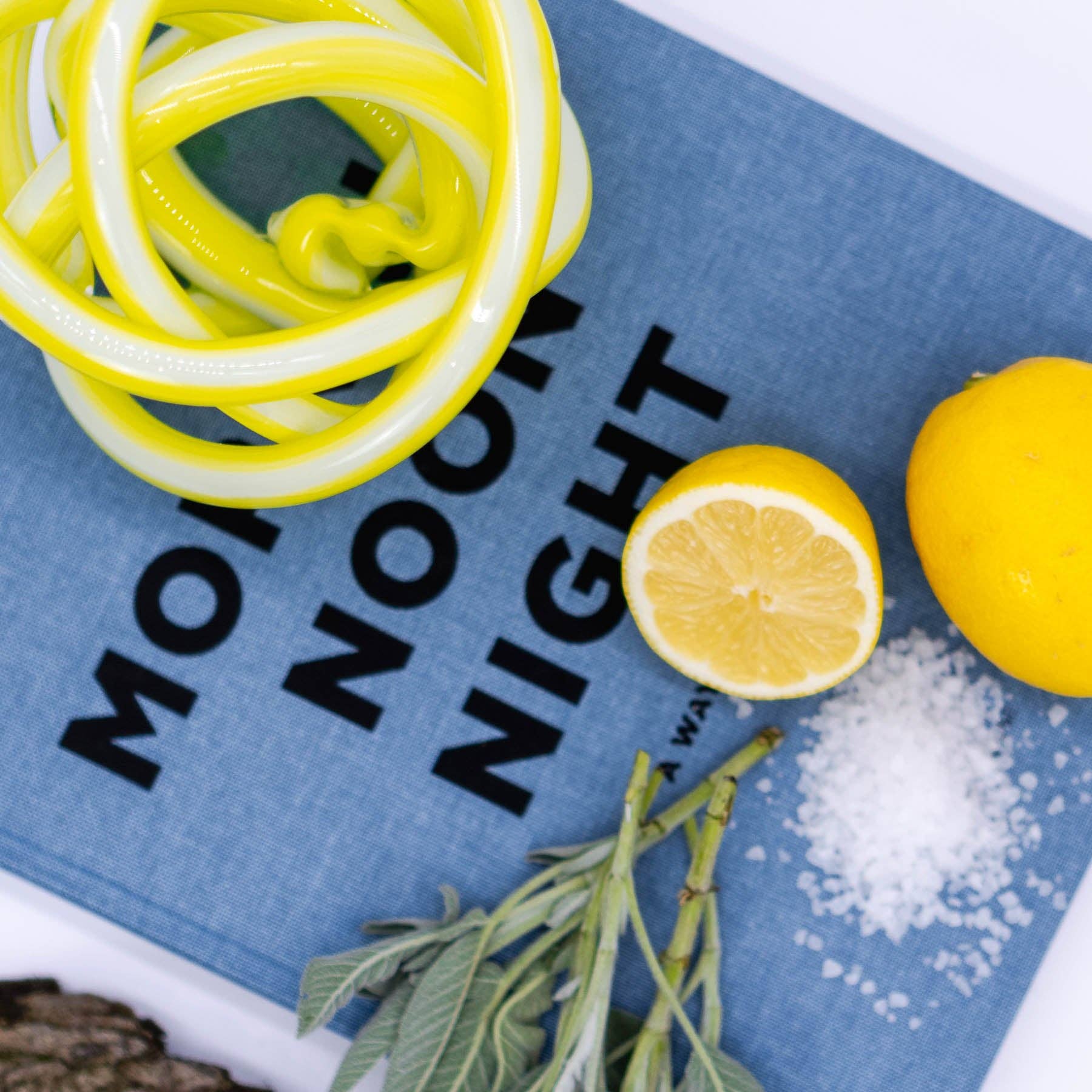 Yuzu slices, lemons, salt, and a sprig of mint on a blue mat with text.