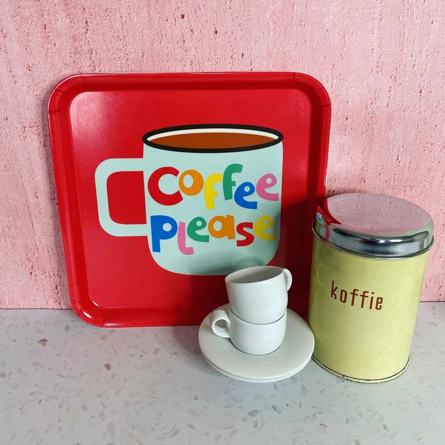 Red tray with 'Coffee Please' design, white cups, and yellow container on a pink background.