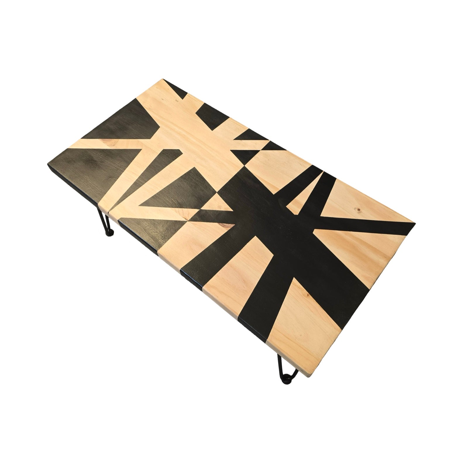 An upcycled coffee table with black hairpin legs and a bold black geometric design on a wooden surface, set against a white background.
