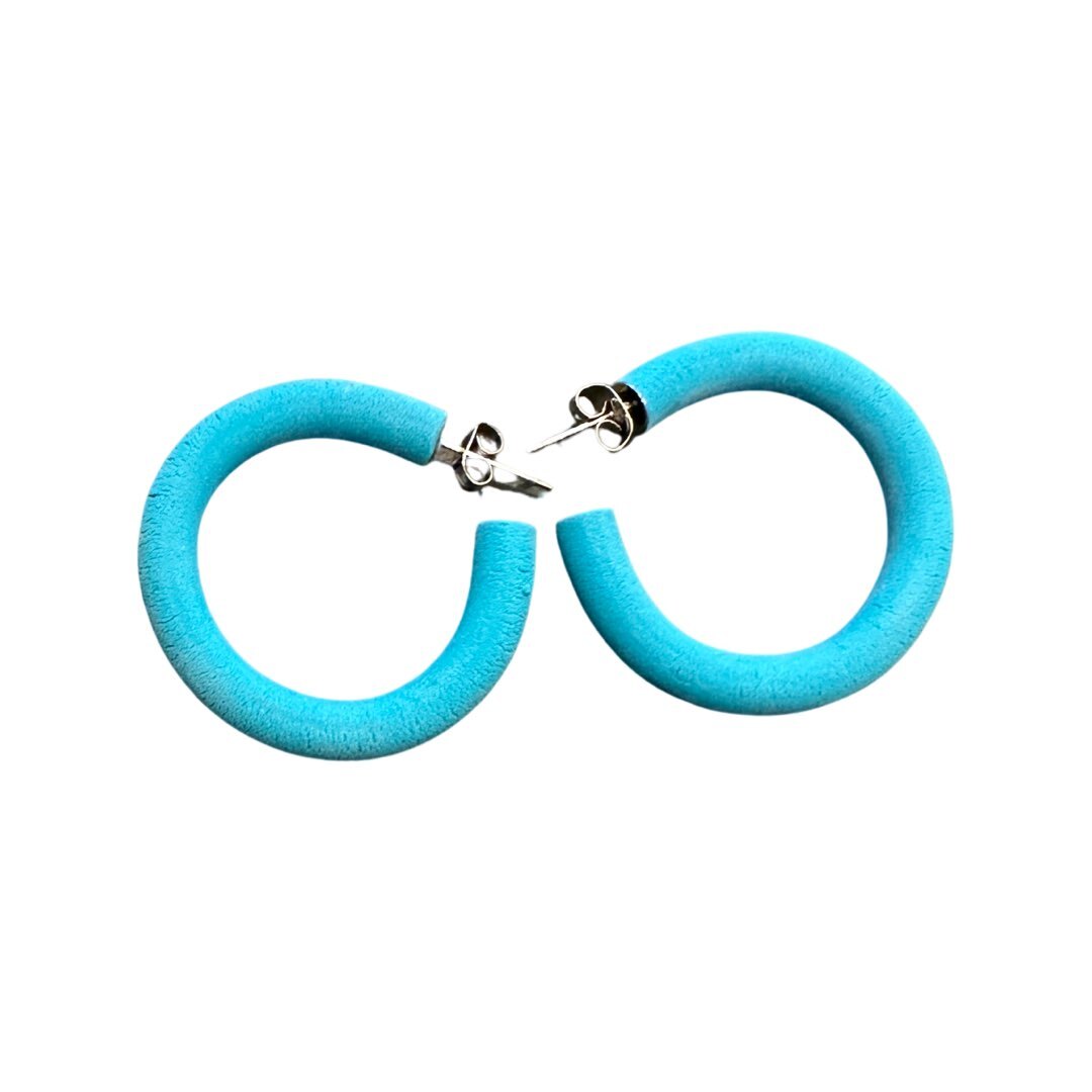 A pair of large turquoise hoop earrings made from polymer clay, displayed against a white background.