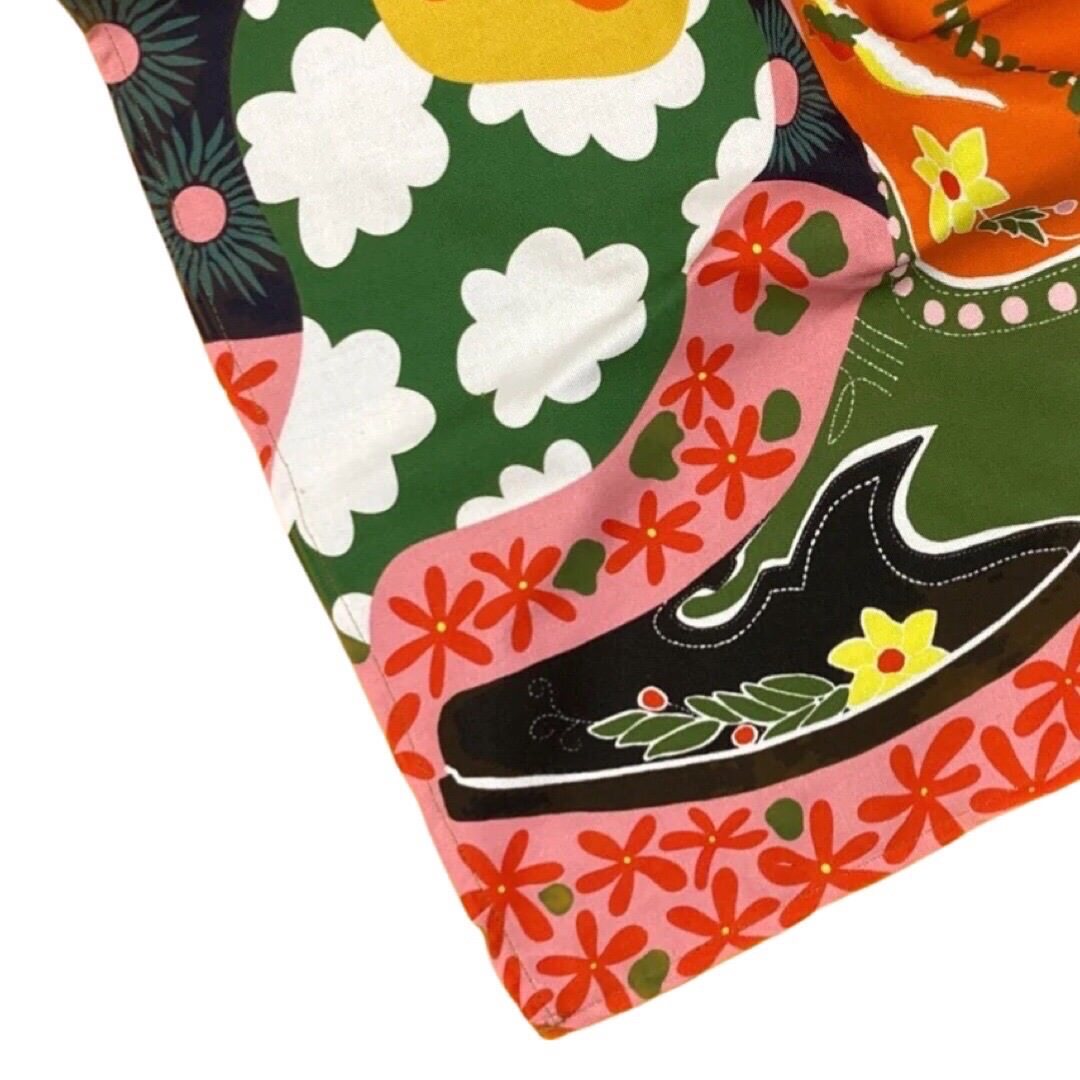 Tea towel featuring a red, black and green cowboy boot surrounded by large yellow and orange flowers and colourful patterns.