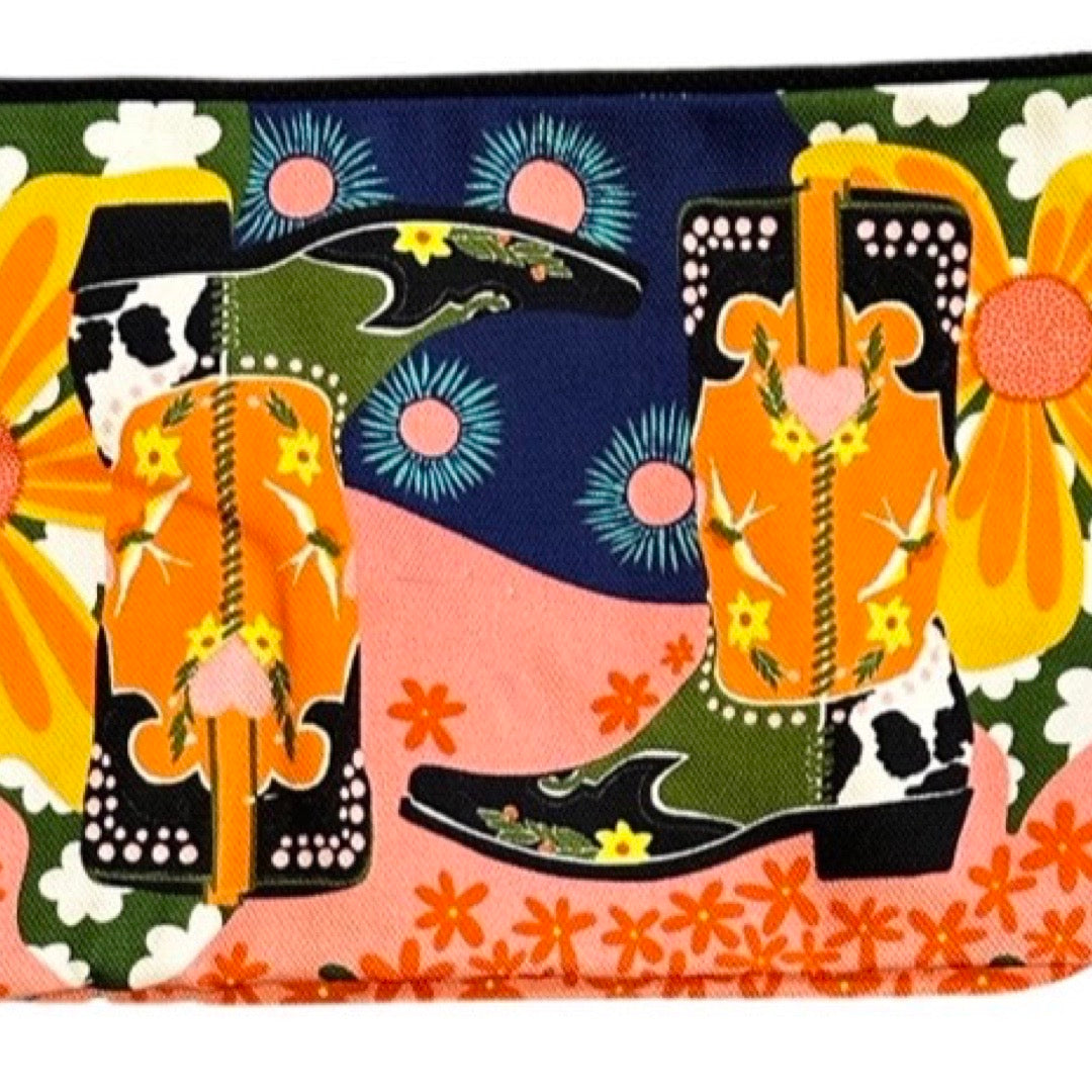 Colorful fabric with cowboy boots, flowers, and cowhide patterns on a multicolored background.