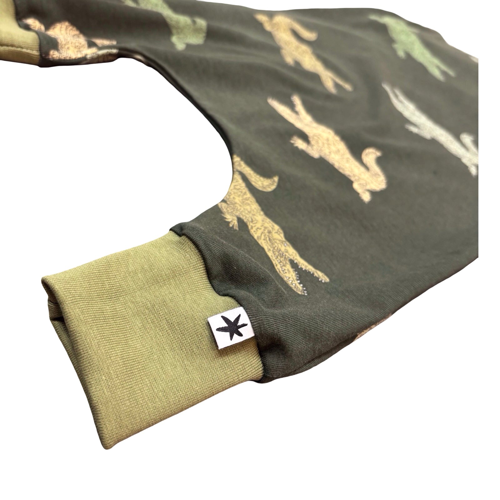 Folded fabric with animal prints on a green background, featuring a brand logo.