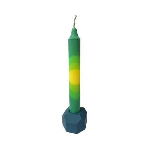 A dark blue cylindrical dinner candle holder with a lip around the bottom to catch any drips holding a blue dinner candle.
