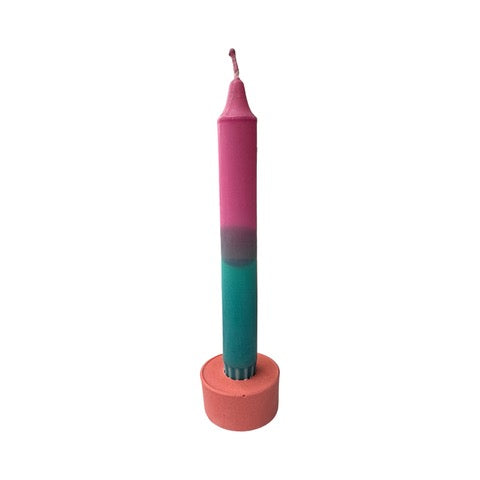 A cylindrical dinner candle holder with a lip around the bottom to catch any drips holding a blue dinner candle.
